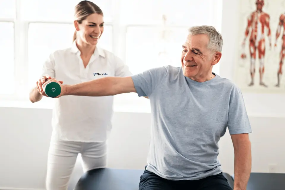 In-home physical therapist guiding a Florida patient through a shoulder strengthening exercise after a car accident.